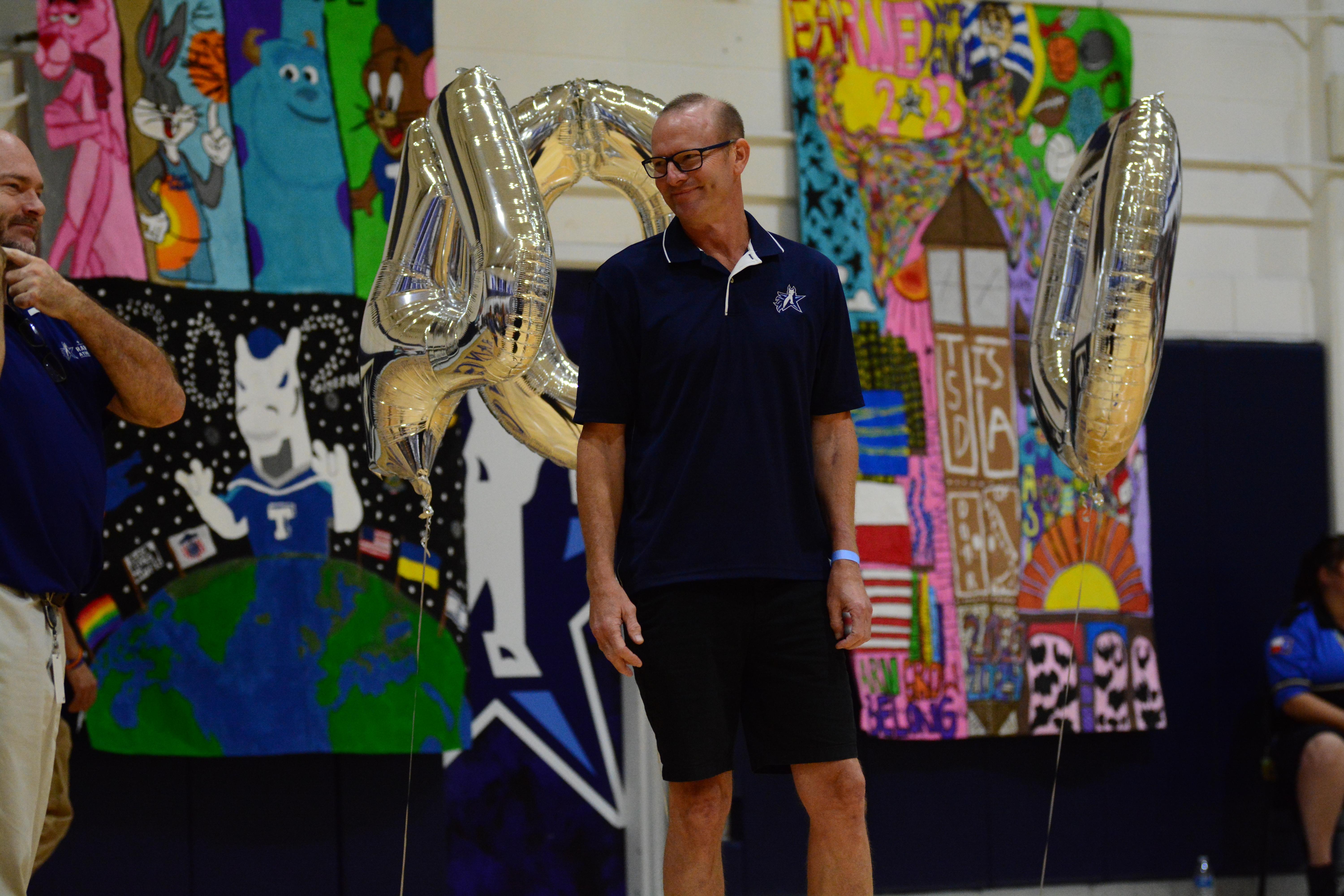 RJ Kaufman is smiling to Chris Hamilton in navy blue polo shirt. The background has three silver balloons that shapes 400.