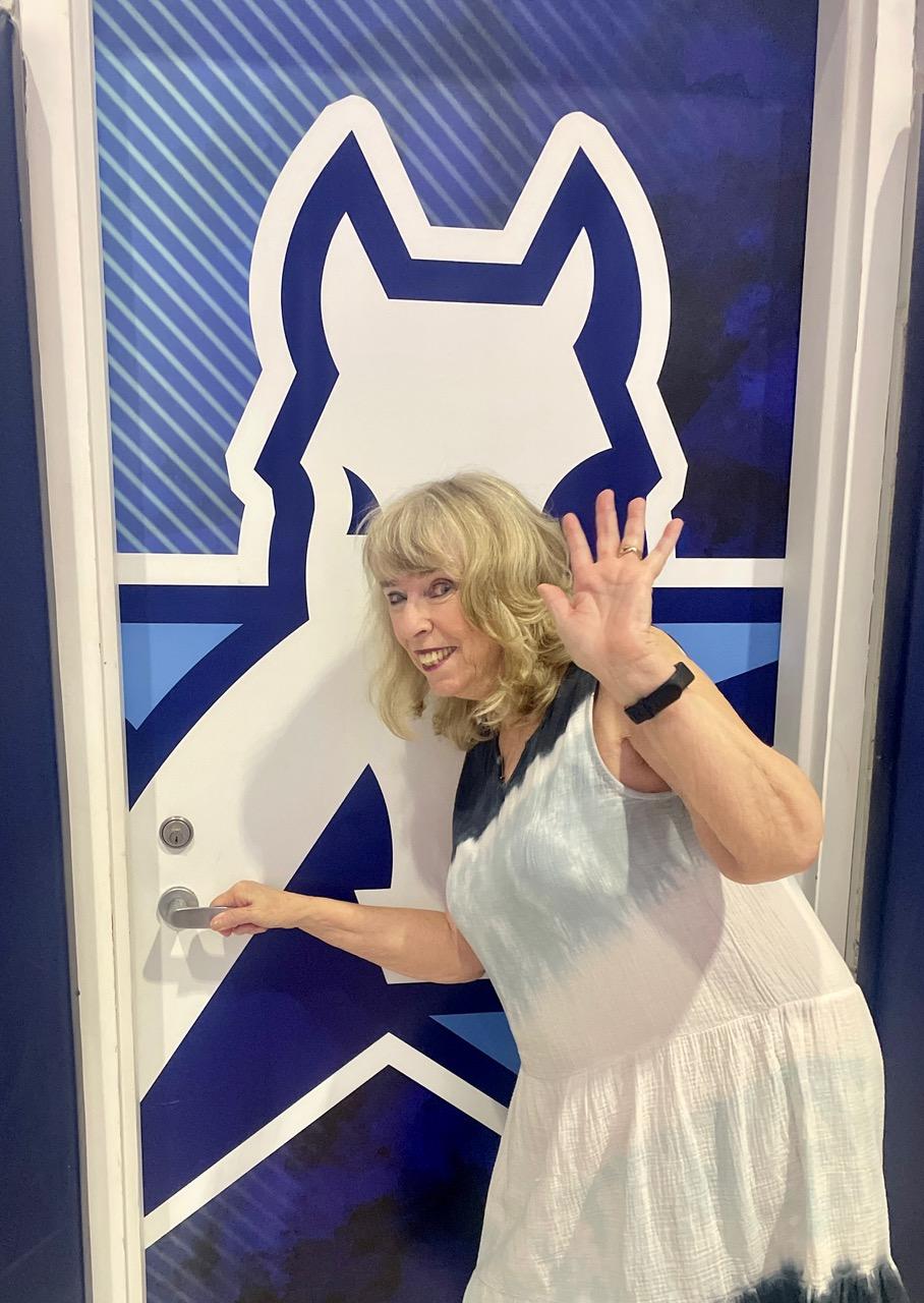 Claire posed the front of the door, waving to the camera and smiling. She wore dyed ombre navy blue to white dress. The background door consists of Ranger logo.