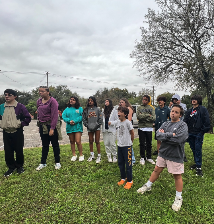 Middle school students watched the presentation from Keep Austin Beautiful, outside of the creek.